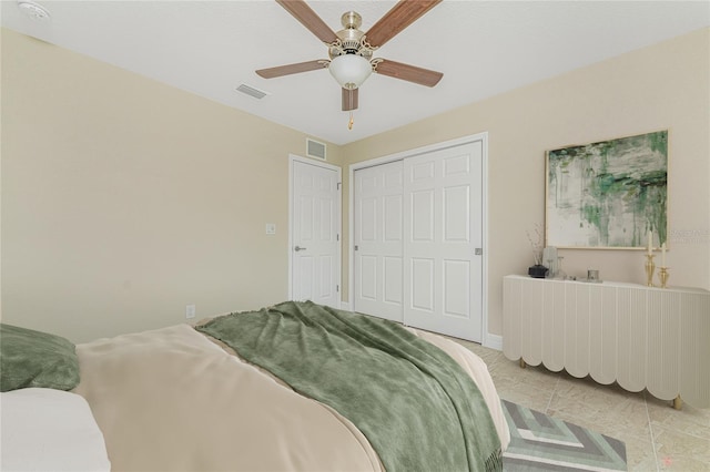 tiled bedroom with ceiling fan and a closet