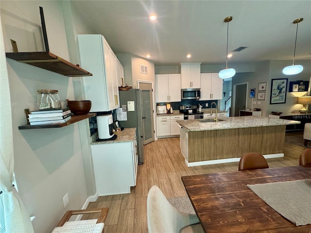 kitchen featuring white cabinetry, light stone countertops, decorative light fixtures, and stainless steel appliances