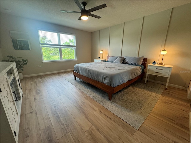 bedroom featuring ceiling fan, a textured ceiling, and light wood-type flooring