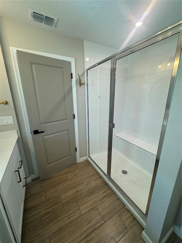 bathroom featuring vanity, an enclosed shower, hardwood / wood-style floors, and a textured ceiling