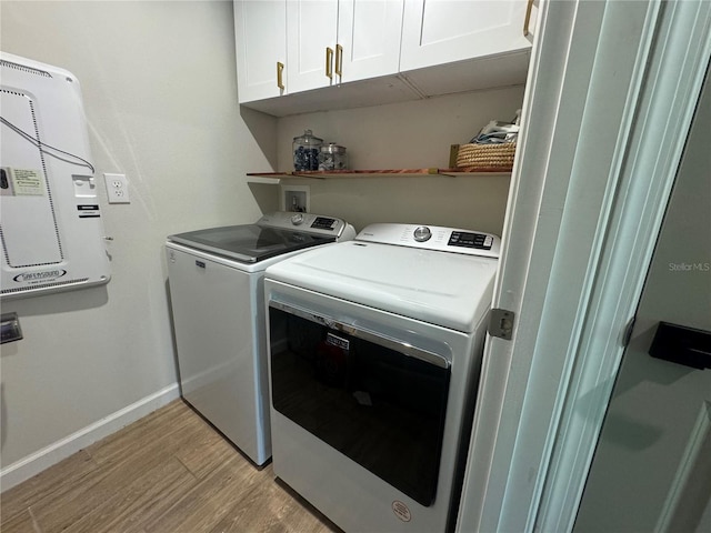 laundry area with cabinets, washing machine and dryer, and light wood-type flooring