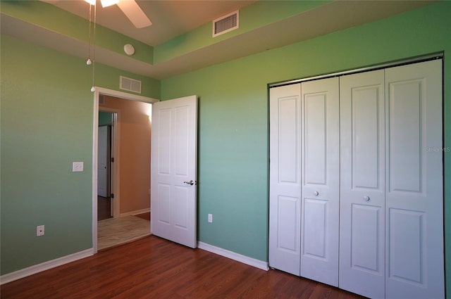 unfurnished bedroom featuring ceiling fan, a closet, and dark wood-type flooring