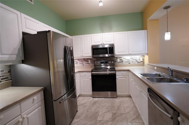 kitchen with appliances with stainless steel finishes, white cabinetry, sink, and decorative light fixtures