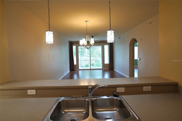 kitchen with hanging light fixtures, arched walkways, open floor plan, and a sink