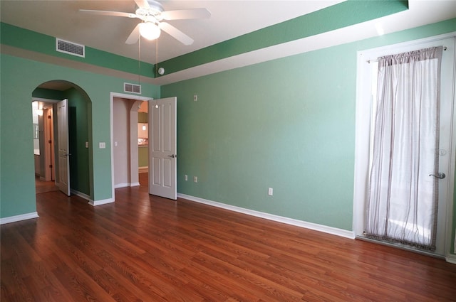 unfurnished room with arched walkways, visible vents, ceiling fan, wood finished floors, and baseboards