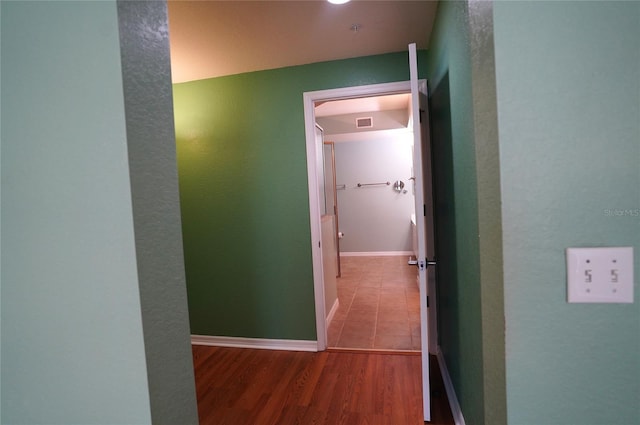 hallway featuring wood finished floors, visible vents, and baseboards