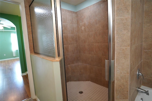 full bath with tiled shower, a tub to relax in, wood finished floors, and baseboards