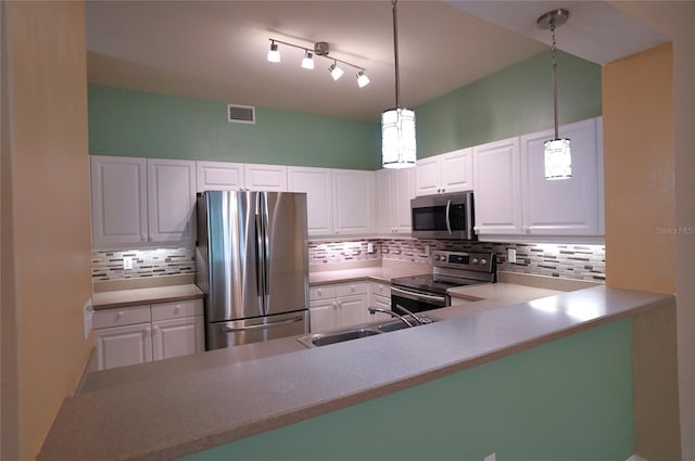 kitchen featuring decorative backsplash, white cabinets, stainless steel appliances, and decorative light fixtures