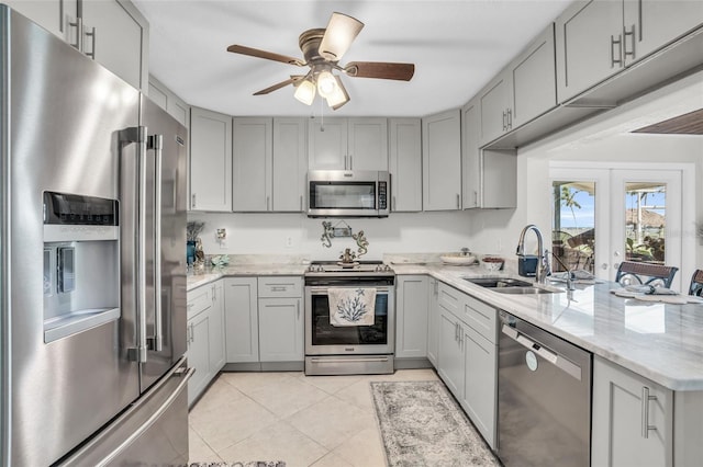 kitchen with gray cabinetry, sink, stainless steel appliances, light stone counters, and light tile patterned floors