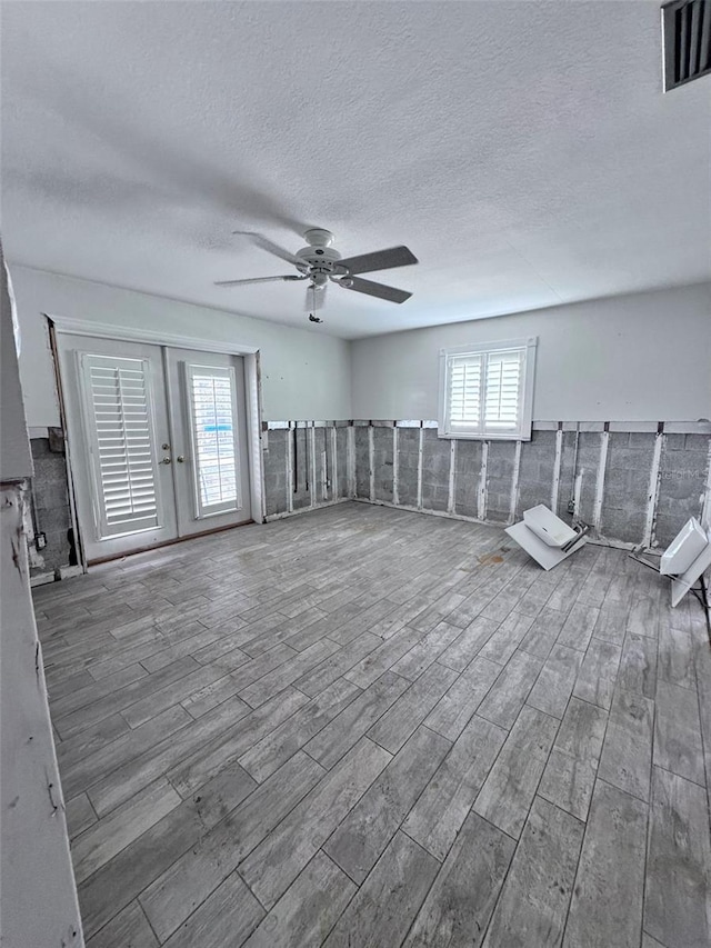 unfurnished room featuring ceiling fan, tile walls, a textured ceiling, and hardwood / wood-style floors