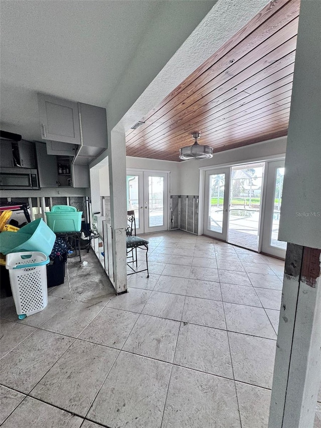 interior space featuring french doors, ceiling fan, wooden ceiling, and light tile patterned flooring