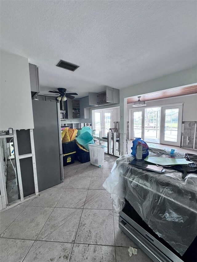 interior space featuring multiple windows, french doors, a textured ceiling, and stainless steel refrigerator