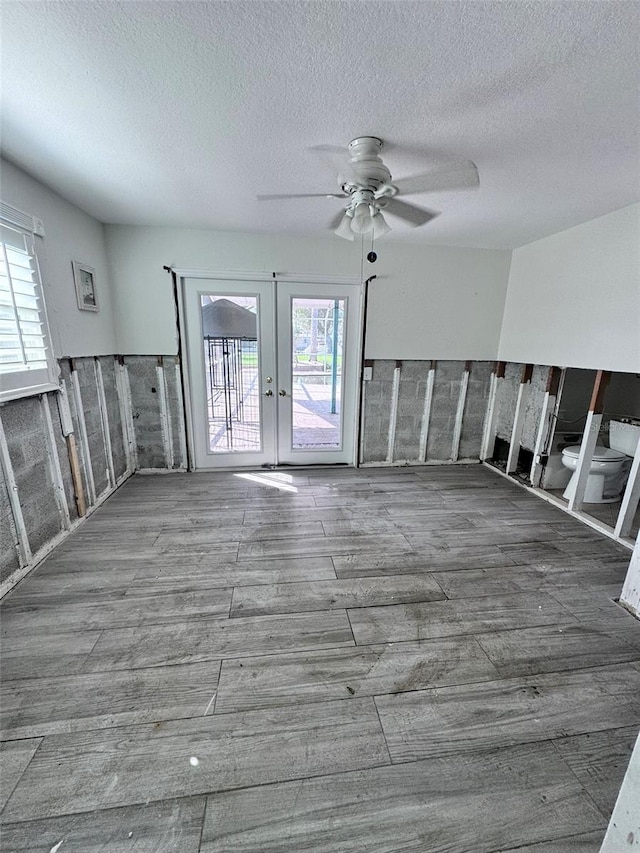 unfurnished room featuring french doors, ceiling fan, a textured ceiling, and plenty of natural light