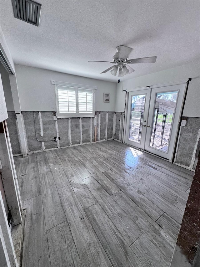 empty room featuring a textured ceiling, a healthy amount of sunlight, and hardwood / wood-style flooring