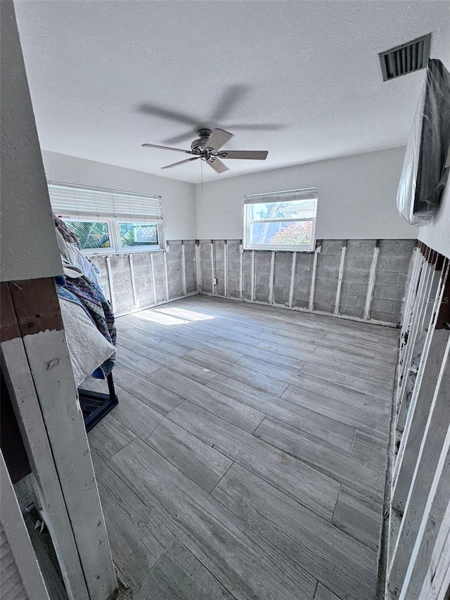 spare room with a textured ceiling, wood-type flooring, and ceiling fan