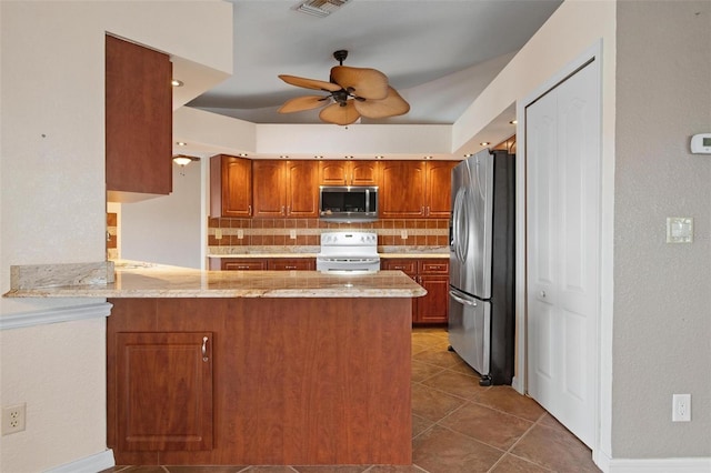 kitchen featuring kitchen peninsula, ceiling fan, stainless steel appliances, tile patterned flooring, and decorative backsplash