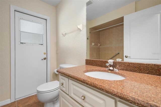 bathroom with tile patterned flooring, vanity, walk in shower, and toilet