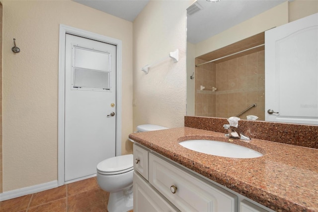 bathroom featuring vanity, tile patterned floors, toilet, and tiled shower