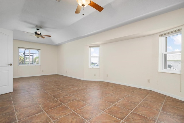 unfurnished room featuring ceiling fan, a healthy amount of sunlight, and dark tile patterned floors