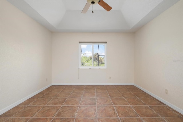 tiled spare room featuring ceiling fan and a raised ceiling