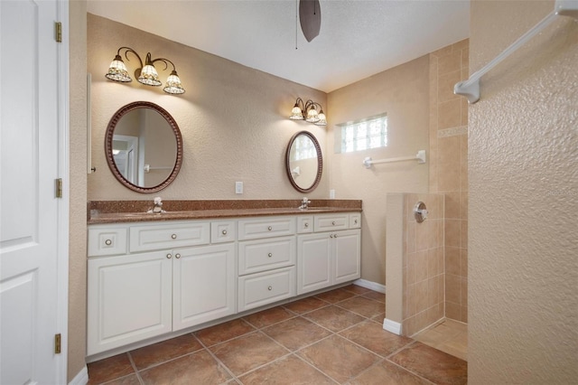 bathroom with tile patterned flooring, vanity, and a tile shower