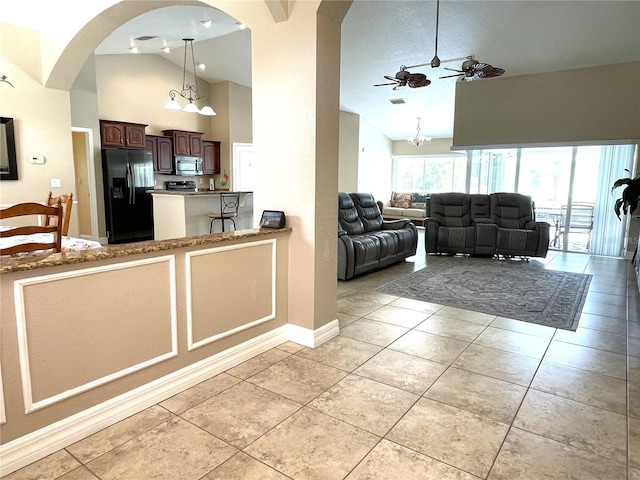 kitchen featuring light tile patterned flooring, high vaulted ceiling, black refrigerator with ice dispenser, kitchen peninsula, and ceiling fan with notable chandelier