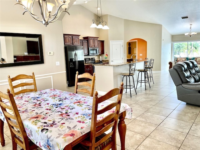 dining area with an inviting chandelier, sink, lofted ceiling, and light tile patterned flooring