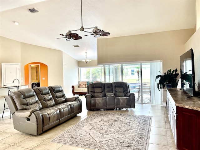 tiled living room featuring lofted ceiling and ceiling fan with notable chandelier