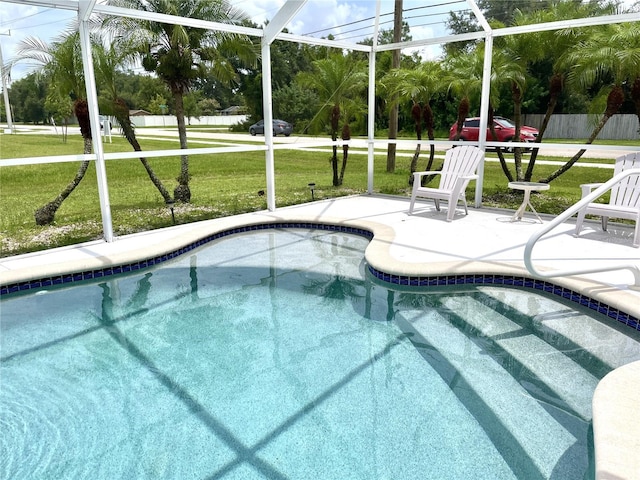 view of pool featuring a patio, glass enclosure, and a lawn