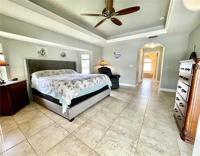 bedroom with a raised ceiling, light tile patterned floors, and ceiling fan