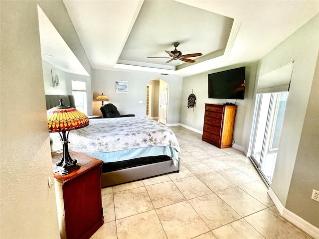 bedroom featuring light tile patterned floors, a tray ceiling, and ceiling fan