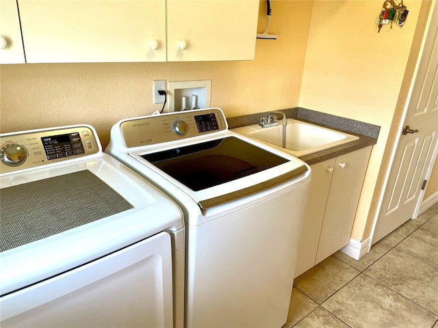 laundry area featuring separate washer and dryer, sink, light tile patterned floors, and cabinets