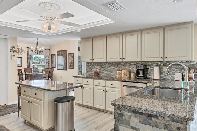 kitchen with light wood-type flooring, sink, a kitchen island, and dark stone countertops