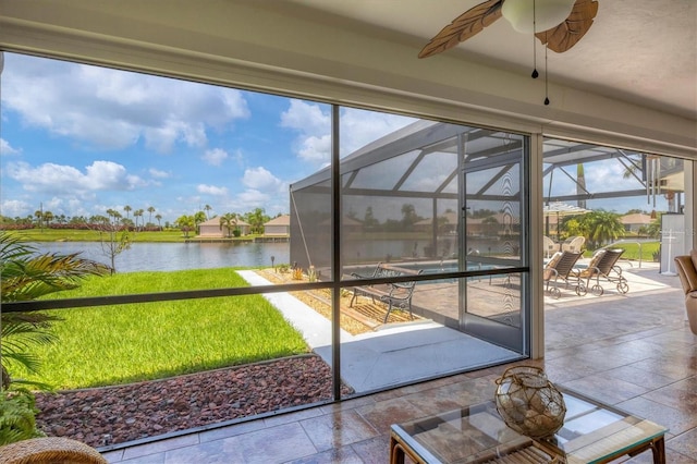 unfurnished sunroom with ceiling fan and a water view