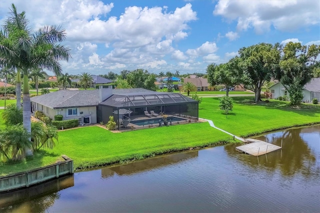 rear view of house with a lanai, a water view, and a lawn