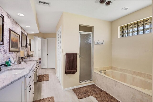 bathroom featuring vanity, plus walk in shower, and wood-type flooring