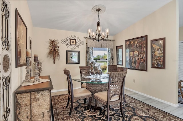 dining room featuring wood-type flooring, a chandelier, and vaulted ceiling