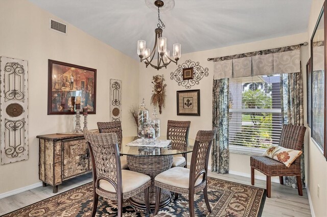 dining room featuring lofted ceiling, a notable chandelier, and light wood-type flooring