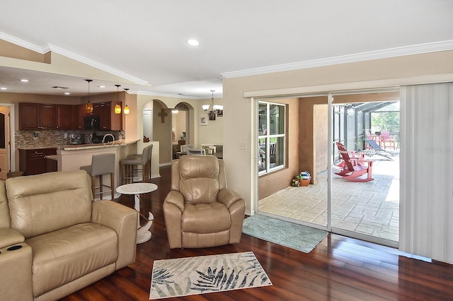 living room with crown molding, vaulted ceiling, dark hardwood / wood-style flooring, and an inviting chandelier