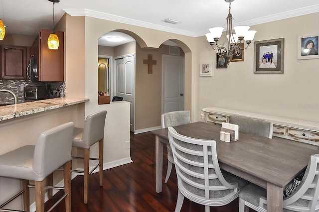 dining room with sink, a chandelier, dark hardwood / wood-style floors, and ornamental molding