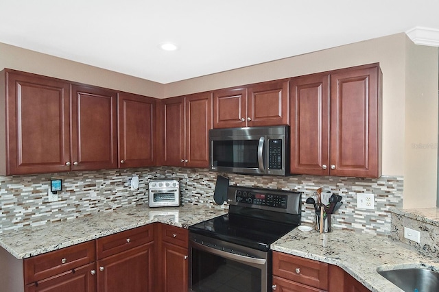 kitchen with decorative backsplash, light stone countertops, appliances with stainless steel finishes, and sink