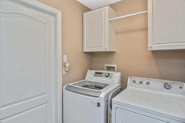 clothes washing area featuring washer and dryer and cabinets