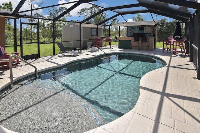 view of swimming pool with an outbuilding, a patio area, exterior bar, and a lanai