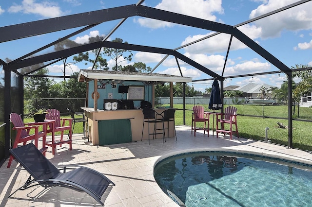 view of pool featuring a bar, a patio, a yard, and glass enclosure