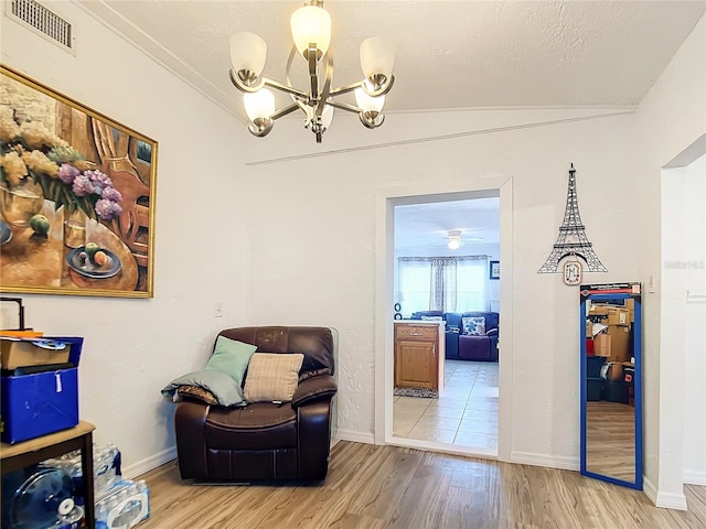 sitting room featuring lofted ceiling, light hardwood / wood-style floors, and ceiling fan with notable chandelier