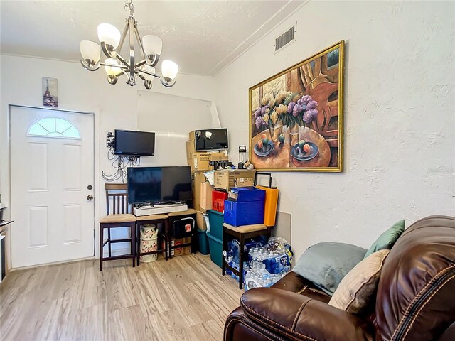 living room with crown molding, light hardwood / wood-style flooring, and a notable chandelier