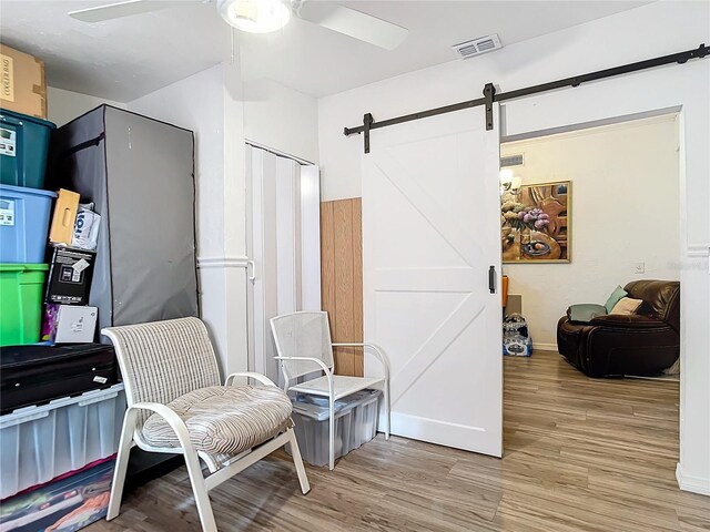 sitting room featuring ceiling fan, a barn door, and hardwood / wood-style floors