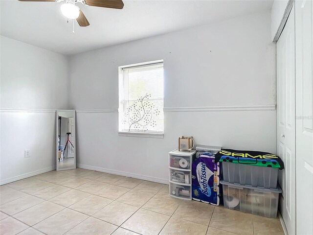 tiled bedroom with ceiling fan and a closet