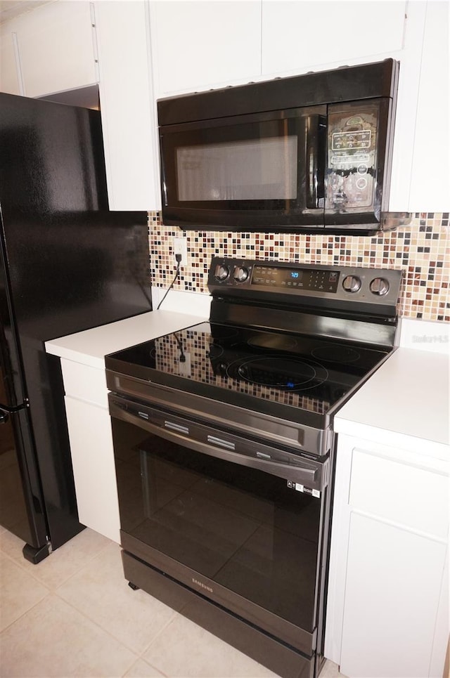 kitchen with white cabinets, backsplash, light tile patterned floors, and electric stove