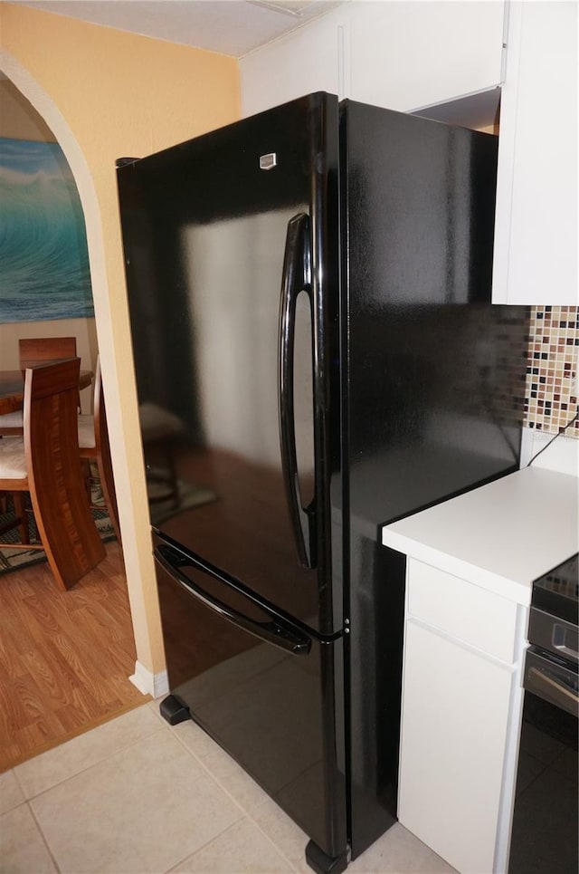 kitchen with light hardwood / wood-style floors, black fridge, white cabinets, and stainless steel electric range